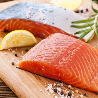 Tranci di salmone fresco con limone e pepe su tagliere